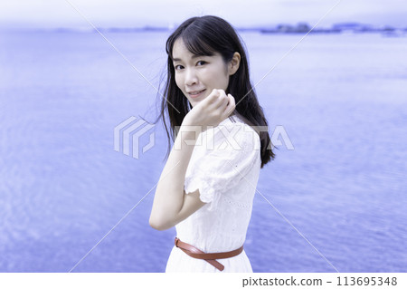 A woman in a white dress strolling by the sea 113695348