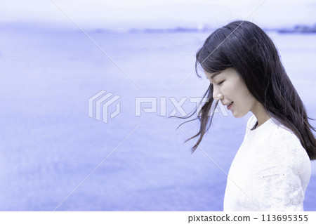 一個穿著白色洋裝的女人在海邊漫步 113695355