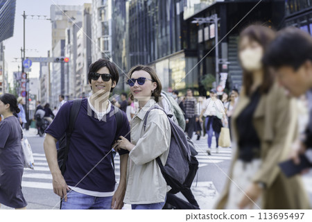Inbound: Foreign tourist couple standing at Ginza Scramble Crossing Inbound: Foreign tourist couple standing at Ginza Scramble Crossing 113695497