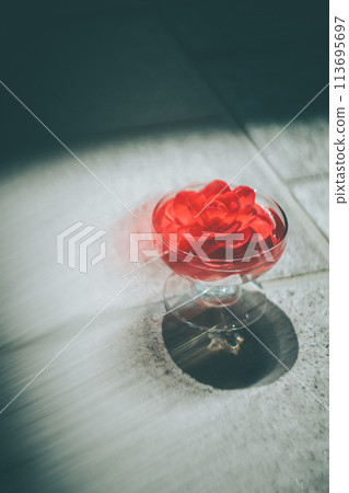 A vibrant red camellia flower floating in a glass vessel A vibrant red camellia flower floating in a glass vessel 113695697