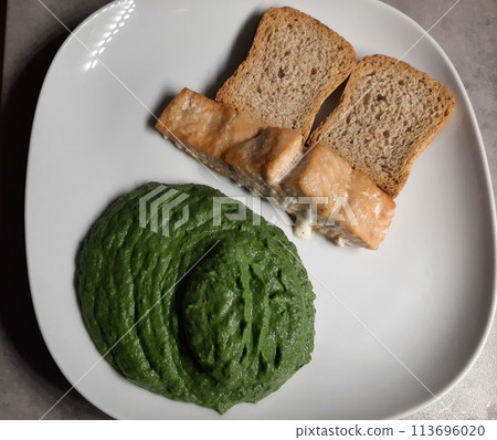 Homemade baked salmon with spinach sauce pure and sliced bred, served on a white plate Homemade baked salmon with spinach sauce pure and sliced bred, served on a white plate 113696020