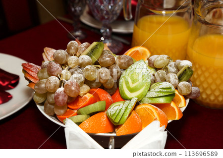 Sliced fruits sprinkled with powdered sugar, creative serving of a dish in a restaurant 113696589
