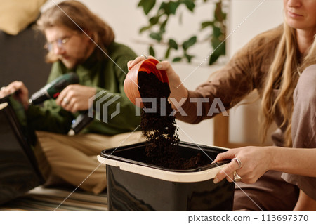 Sprinkling soil from bowl into bucket Sprinkling soil from bowl into bucket 113697370