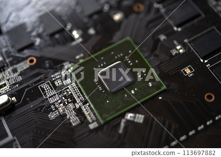 A brown printed circuit board with a processor chip and video memory strips. Electronic components on the graphics card. A brown printed circuit board with a processor chip and video memory strips. Electronic components on the graphics card. 113697882
