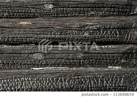 Texture (background, pattern) of a black charred log wall of a burned-out wooden house. Texture (background, pattern) of a black charred log wall of a burned-out wooden house. 113698659