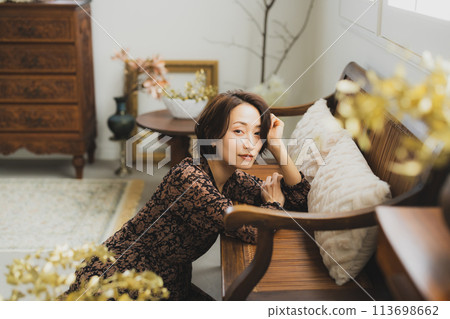 Middle-aged woman sitting on a sofa in a room Middle-aged woman sitting on a sofa in a room 113698662