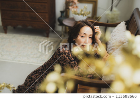 Middle-aged woman sitting on a sofa in a room 113698666