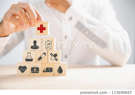 Wooden block with healthcare and medical icons held by hand. Illustrating safety, health, and family care, symbolizing pharmacy, heart well-being, and happiness. health care concept 113698687