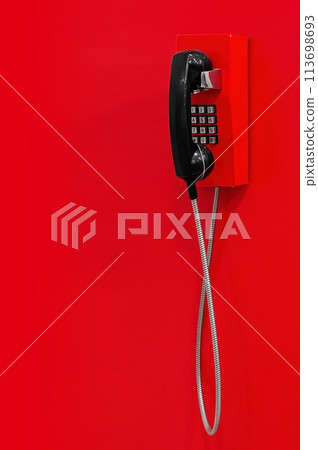 Red wall telephone (taxophone) on red background. Emergency call to 112, 911,  fire and rescue, medic, police, urgent message. 113698693