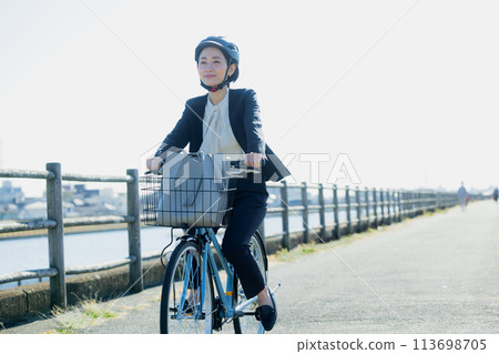 Middle-aged woman commuting to work on a bicycle Middle-aged woman commuting to work on a bicycle 113698705