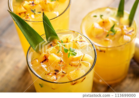 Grilled pineapple cocktail in tall glasses garnished with pineapple leaves 113699000