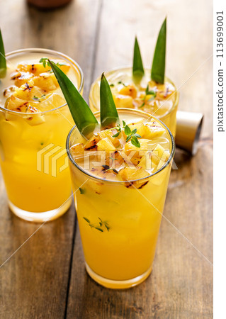 Grilled pineapple cocktail in tall glasses garnished with pineapple leaves Grilled pineapple cocktail in tall glasses garnished with pineapple leaves 113699001