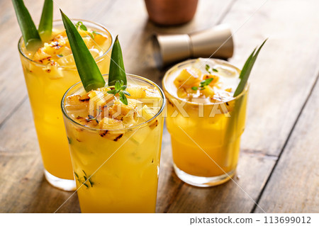 Grilled pineapple cocktail in tall glasses garnished with pineapple leaves 113699012