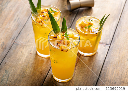 Grilled pineapple cocktail in tall glasses garnished with pineapple leaves 113699019