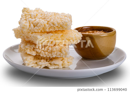 Closeup view stack of crispy rice crackers with peanut sauce in brown ceramic cup. Closeup view stack of crispy rice crackers with peanut sauce in brown ceramic cup. 113699040