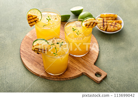 Grilled pineapple margarita garnished with lime wedges Grilled pineapple margarita garnished with lime wedges 113699042