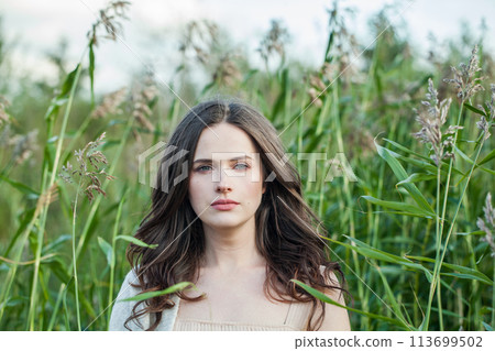 One healthy young brunette woman with fresh clear skin and long dark brown hair outdoors 113699502