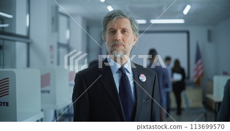 Businessman poses and looks at camera in polling station 113699570