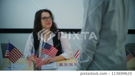 Female polling officer talks with African American male voter and gives bulletin Female polling officer talks with African American male voter and gives bulletin 113699620