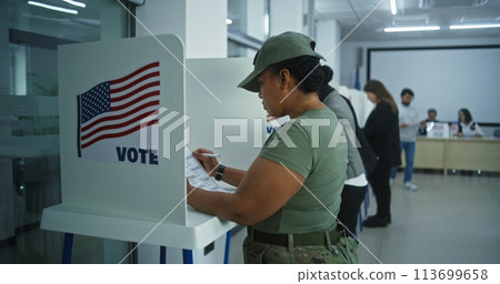 Female American army soldier votes in booth in polling station Female American army soldier votes in booth in polling station 113699658