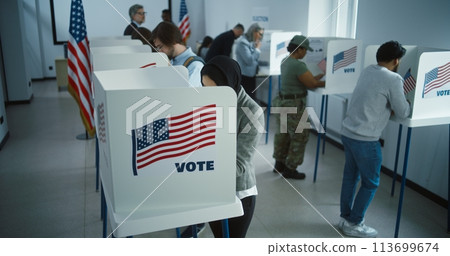 Arabic woman in hijab votes in booth in polling station office 113699674