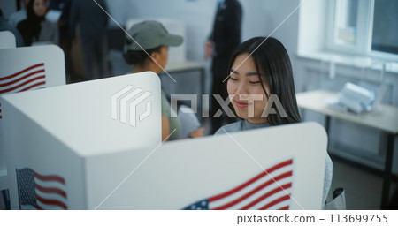 Asian female American citizen votes in booth in polling station 113699755
