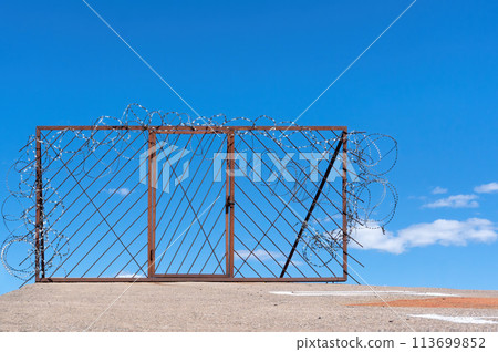 Door and fence with barbed razor wire against the sky. No entrance to heavens concept. 113699852