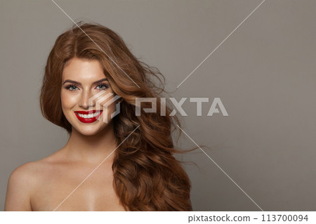 Cheerful fashionable redhead woman with long wavy hair and make-up. Studio headshot portrait  113700094