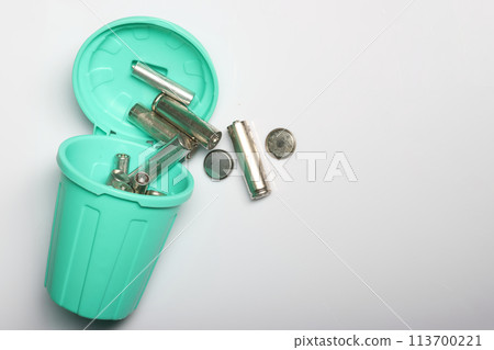 Thought-provoking photo of finger batteries in a mini bin, showcasing the need for proper disposal methods to protect our environment. on a white background. Thought-provoking photo of finger batteries in a mini bin, showcasing the need for proper disposal methods to protect our environment. on a white background. 113700221