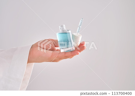 Blue serum with pipette in a womans hands in a robe. 113700400