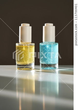 Yellow and blue serums with pipettes against the background of the sun. 113700401