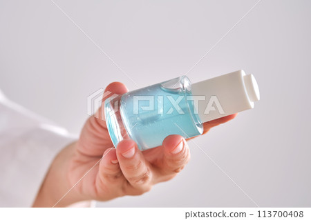 Blue serum with pipette in a womans hands in a robe. Blue serum with pipette in a womans hands in a robe. 113700408