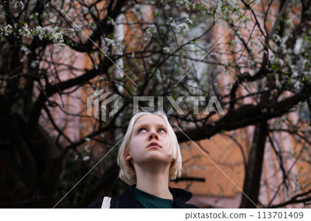 Stylish young woman in spring against blossom tree flowers background 113701409