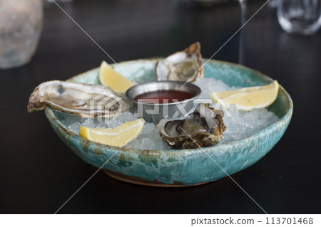 Oysters with fresh lemon and ice on black wooden table background 113701468