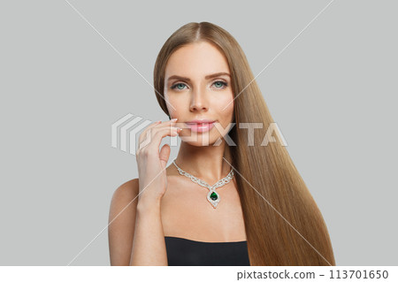 Smiling woman with makeup wearing jewelry necklace with sapphire and diamond on grey background 113701650