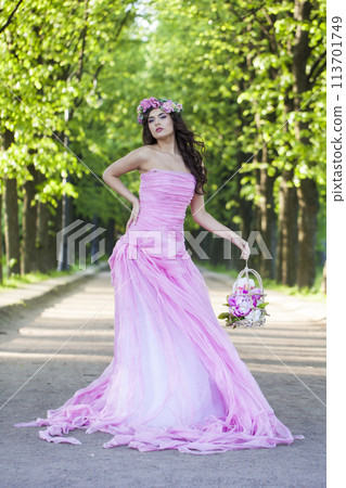 Posing female model with bright makeup, curly hair and pink flower wreath 113701749