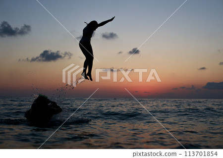 Happy family on sea beach. Happy vacation and holidays concept. Young girl jumping in the sea Happy family on sea beach. Happy vacation and holidays concept. Young girl jumping in the sea 113701854