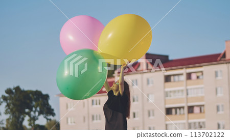 A girl happily poses with large with colorful balloons in the city. A girl happily poses with large with colorful balloons in the city. 113702122