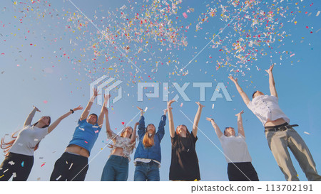 Friends toss colorful paper confetti from their hands. 113702191