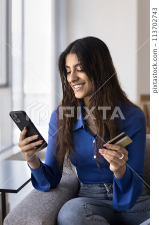 Cheerful young Indian consumer woman making payment for online purchase Cheerful young Indian consumer woman making payment for online purchase 113702743