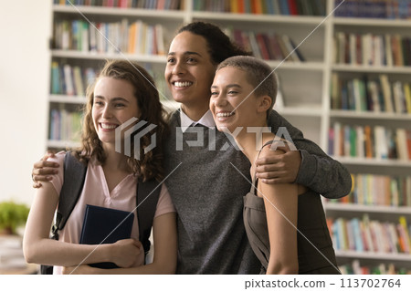Happy multiethnic students hugging standing together in high-school library Happy multiethnic students hugging standing together in high-school library 113702764