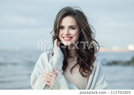 Happy brunette lady outdoor portrait. Healthy woman against blue sea and sky background Happy brunette lady outdoor portrait. Healthy woman against blue sea and sky background 113702805