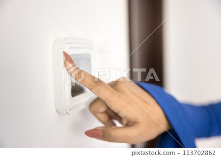 Young woman using climate control panel at home 113702862