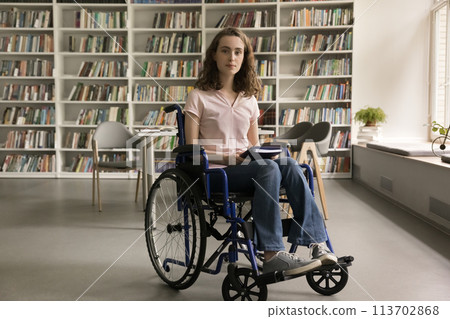 Student girl with mobility impairment posing for camera in library 113702868