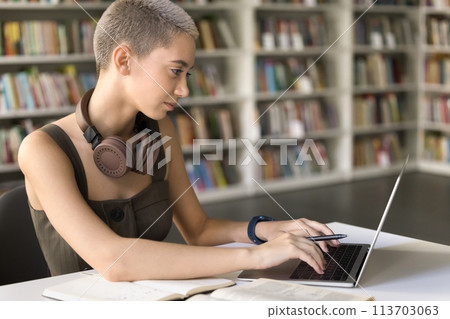 Student girl studying in university library typing on laptop Student girl studying in university library typing on laptop 113703063