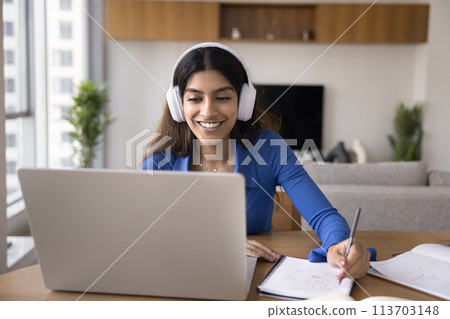 Cheerful Indian student girl in headphones talking on video call Cheerful Indian student girl in headphones talking on video call 113703148