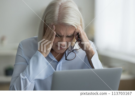Woman sit near laptop take off glasses suffers from migraine Woman sit near laptop take off glasses suffers from migraine 113703167