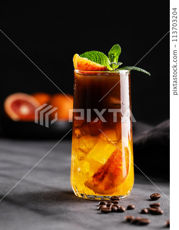 Coffee with orange juice (bumble) in a tall glass with ice and mint on a dark background Coffee with orange juice (bumble) in a tall glass with ice and mint on a dark background 113703204