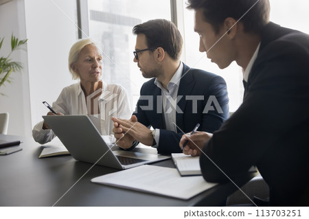 Group of businesspeople lead conversation sit at desk with laptop Group of businesspeople lead conversation sit at desk with laptop 113703251
