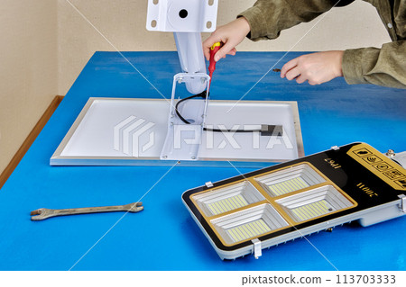Assembler attaches solar module to stand alone solar streetlight. 113703333